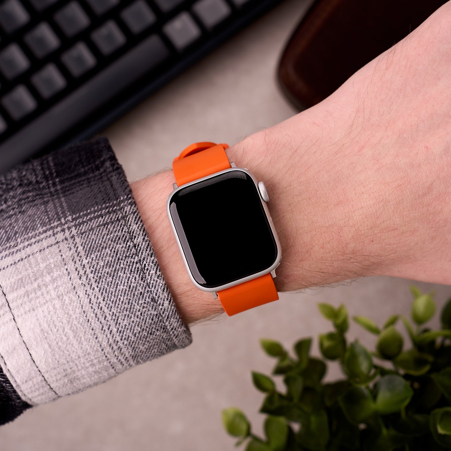 The Callaway FKM rubber Apple Watch band in Orange worn on the wrist with an Apple Watch