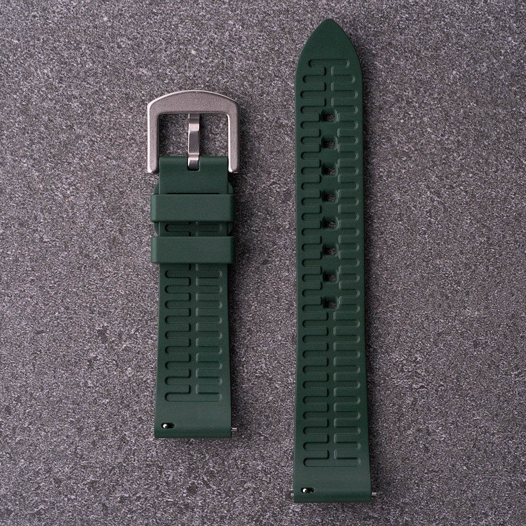 Underside close-up of The Callaway forest green FKM rubber strap showing ventilation grooves and quick-release bars for 18mm 20mm 22mm and 24mm lugs.