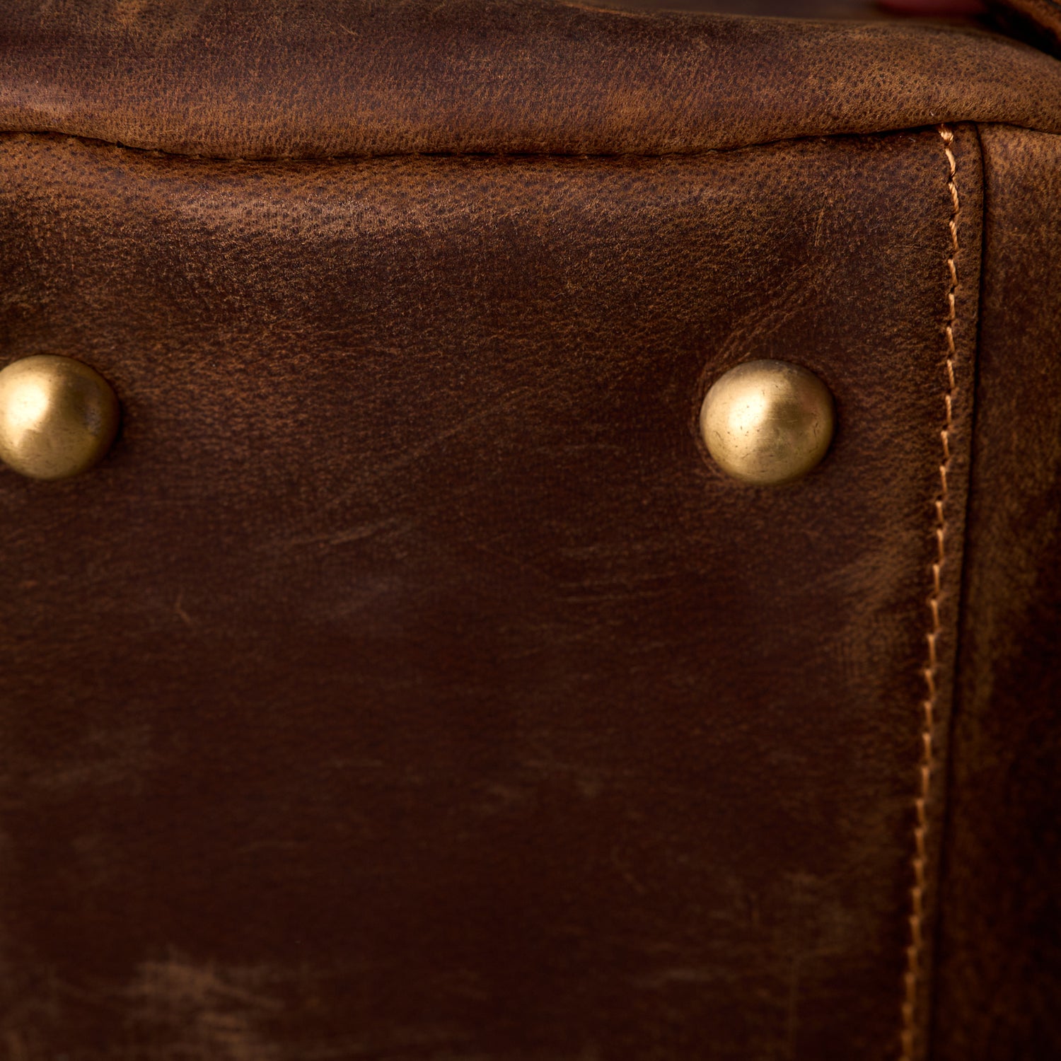 Close up of the crazy horse leather grain and brass base rivets on The Grafton toiletry bag
