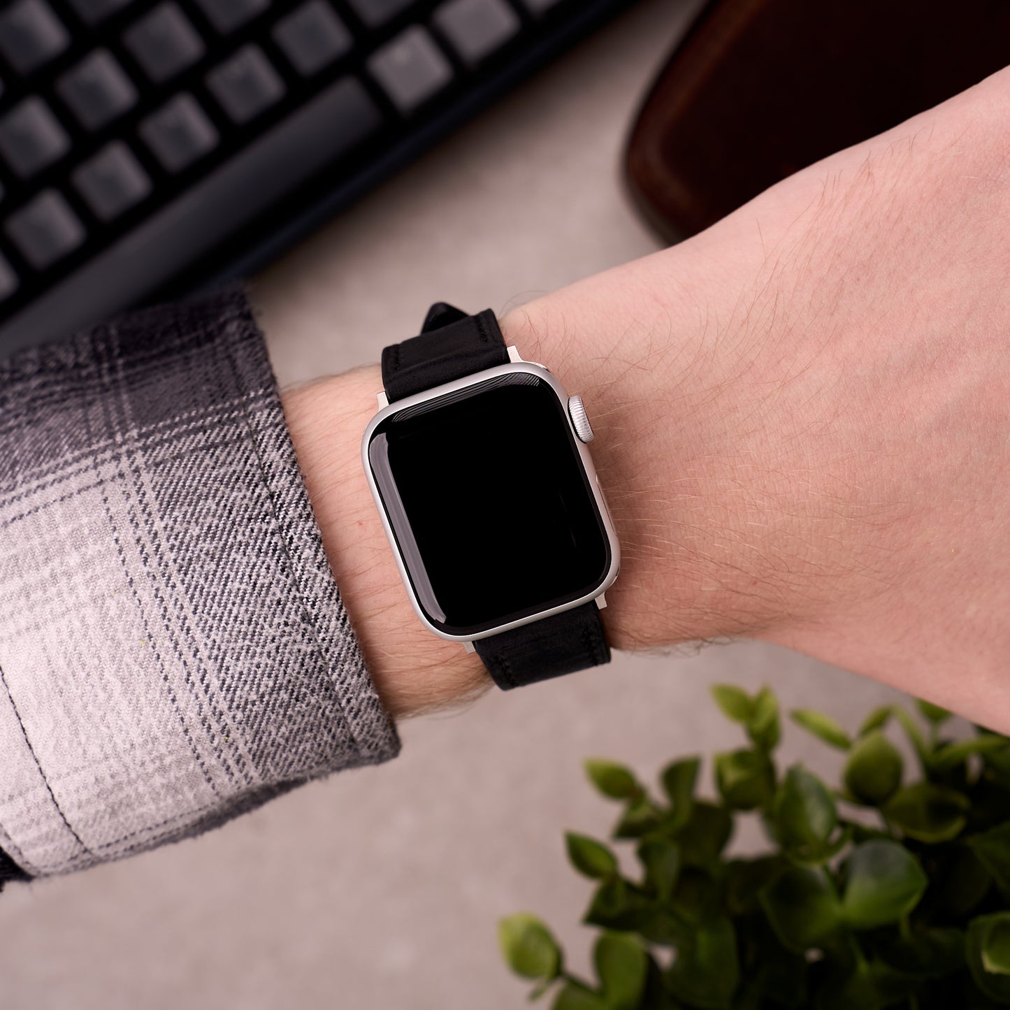 The Harrington leather Apple Watch band in Black worn on the wrist with an Apple Watch