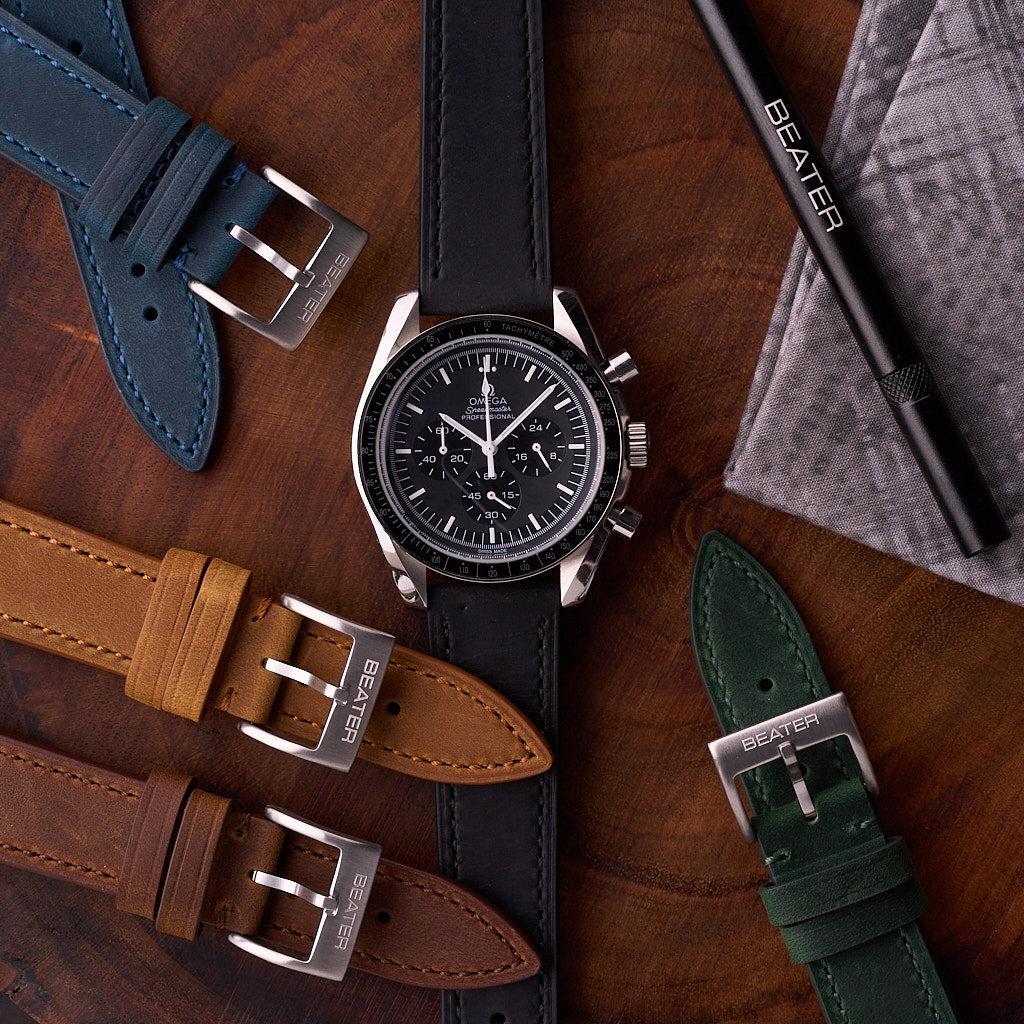 Black Harrington leather strap on a watch beside other leather bands in blue, green, brown and tan, forming a timeless leather watch bracelet lineup.