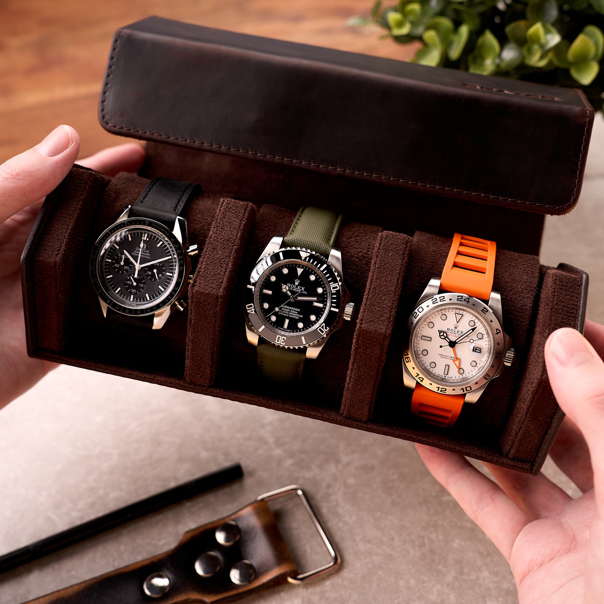 The Ashford leather watch roll held open in two hands, loaded with three watches