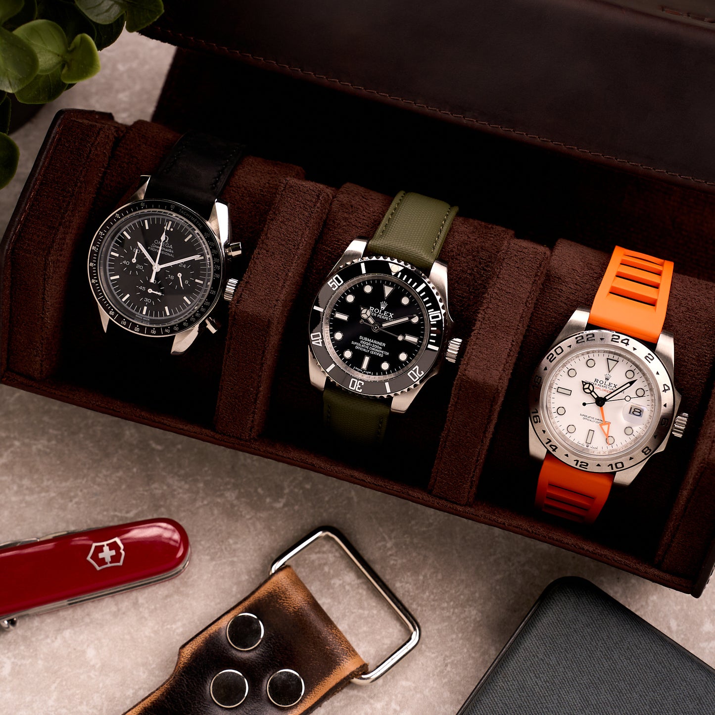 The Ashford watch roll open on a desk beside a pocket knife and a leather watch strap