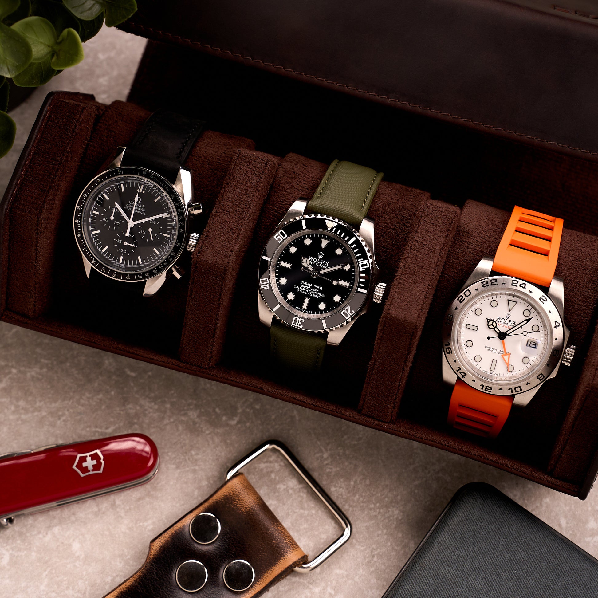 The Ashford watch roll open on a desk beside a pocket knife and a leather watch strap