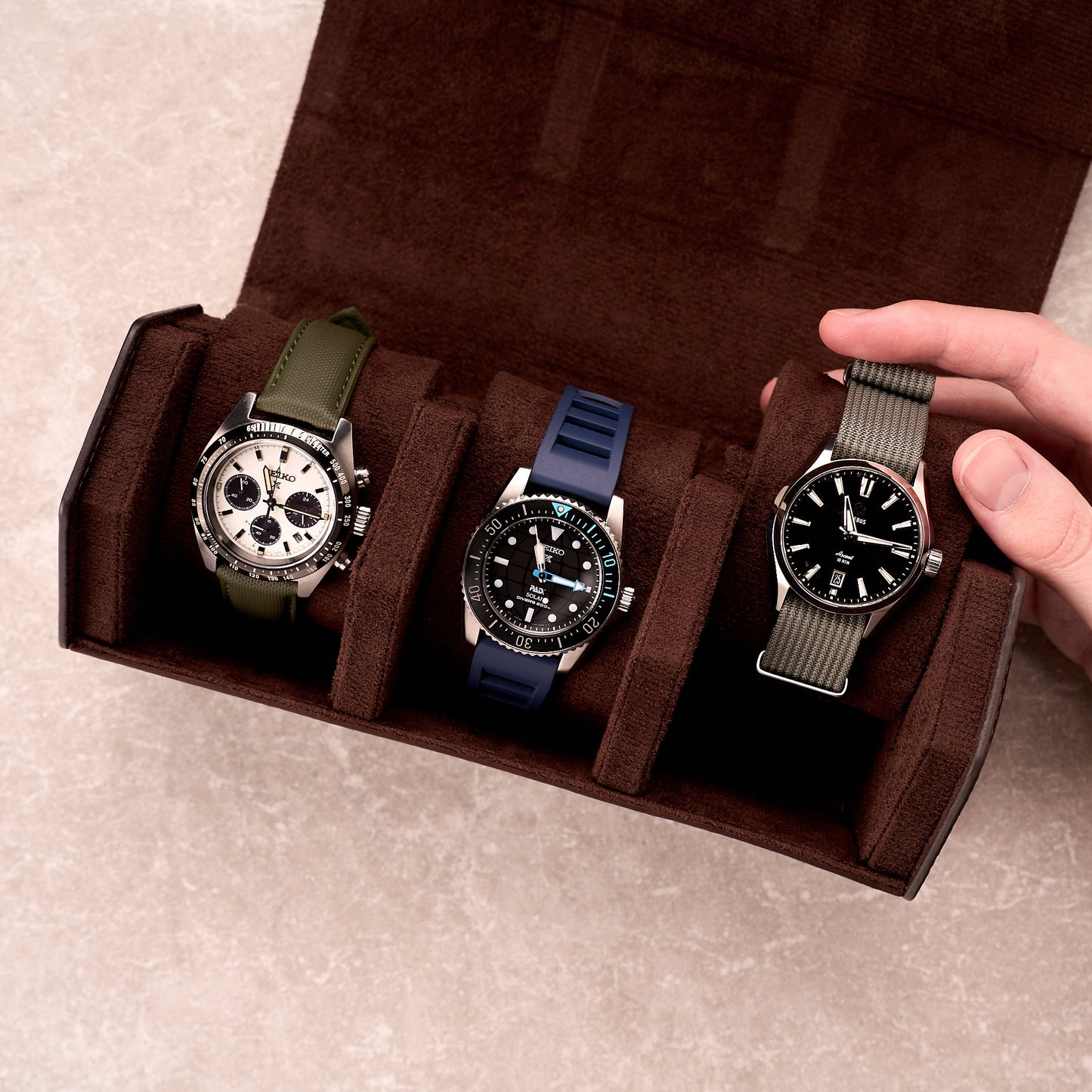 The Ashford watch roll open holding three watches on green, blue and black straps