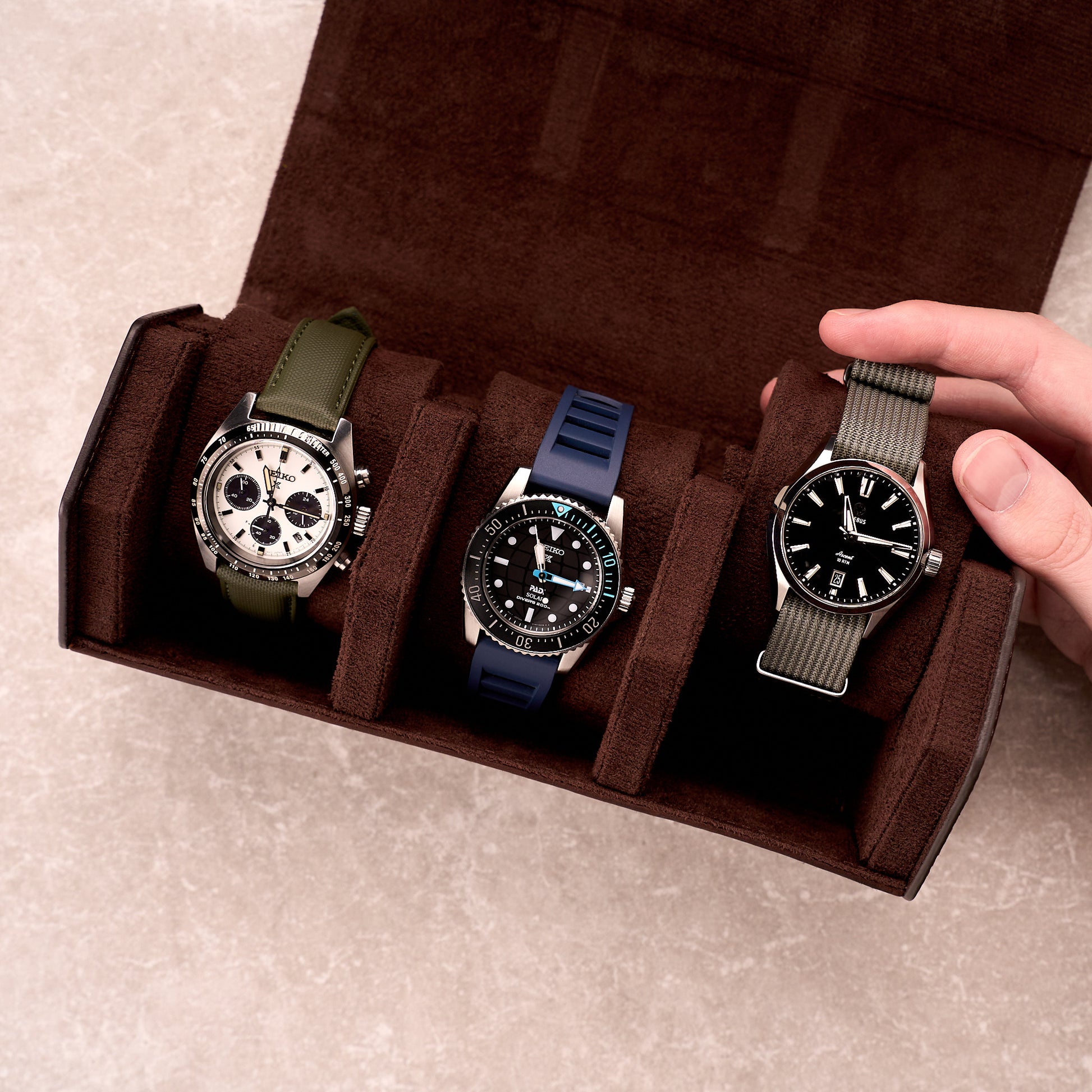 The Ashford watch roll open holding three watches on green, blue and black straps