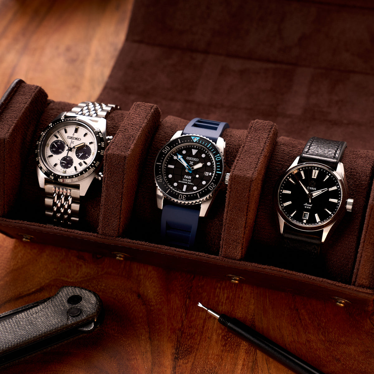 The Ashford leather watch roll open on a timber desk holding three watches