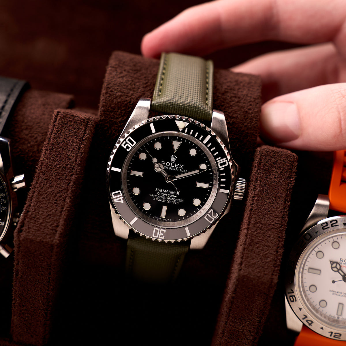 A hand lowering a dive watch into one of the slots in The Ashford leather watch roll