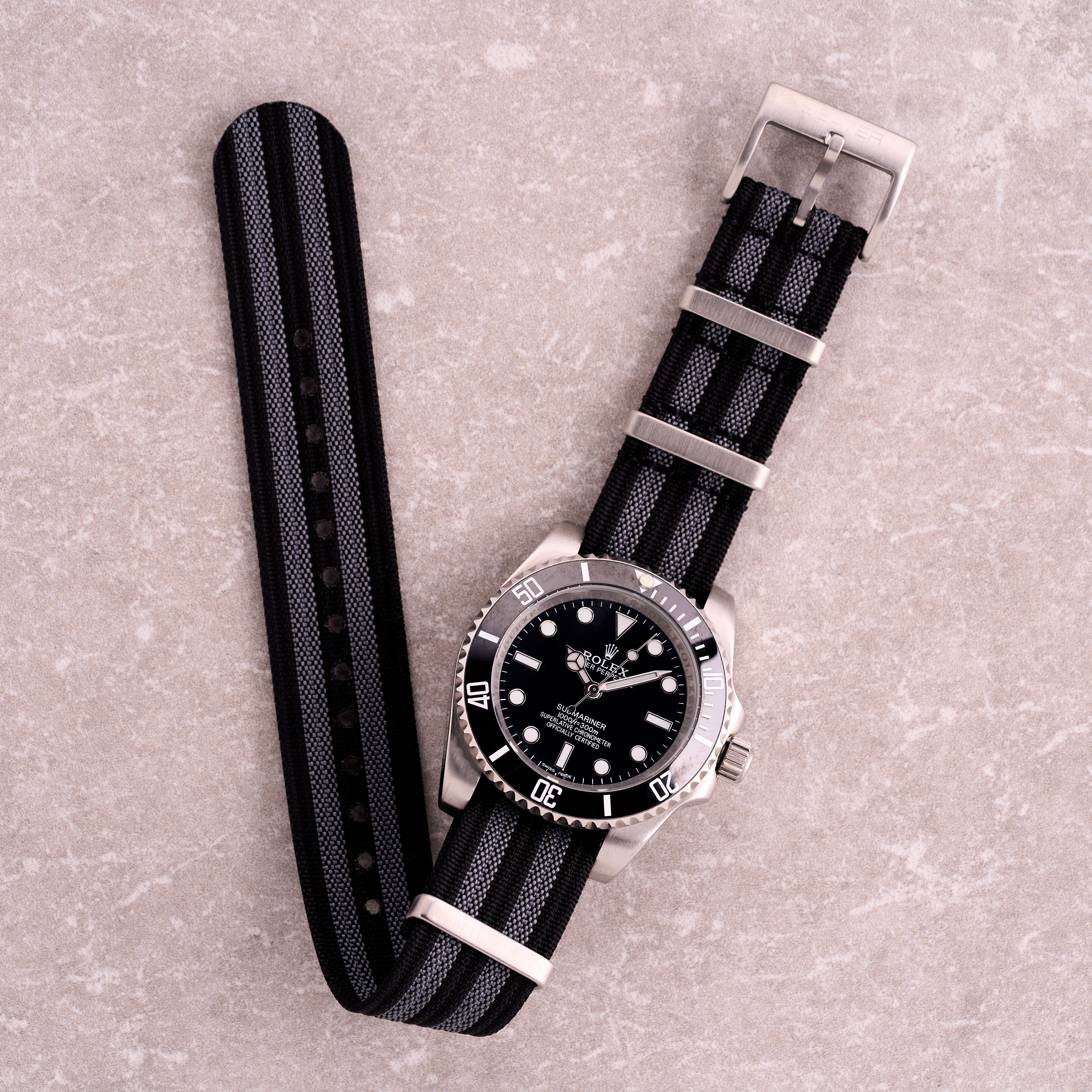 The Operator James Bond black and grey stripe NATO strap, striped nylon one-piece watch band with corrugated texture and steel hardware.