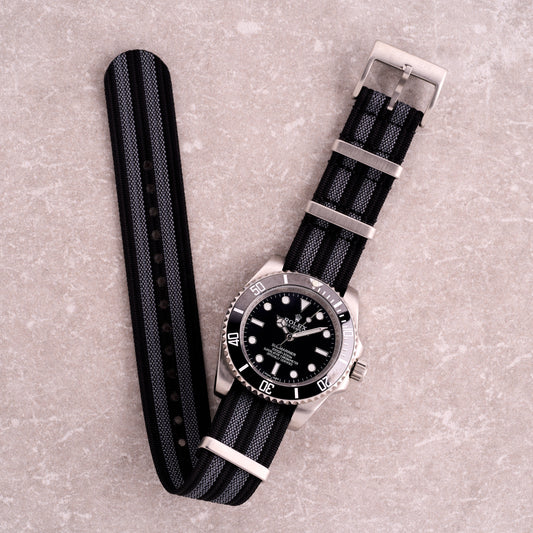 The Operator James Bond black and grey stripe NATO strap, striped nylon one-piece watch band with corrugated texture and steel hardware.