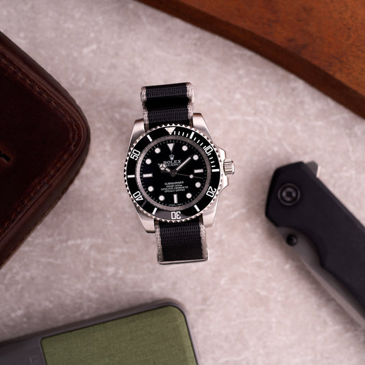 Diver watch on The Sentinel black with grey edge seatbelt NATO strap, giving a refined tactical look on wrist.