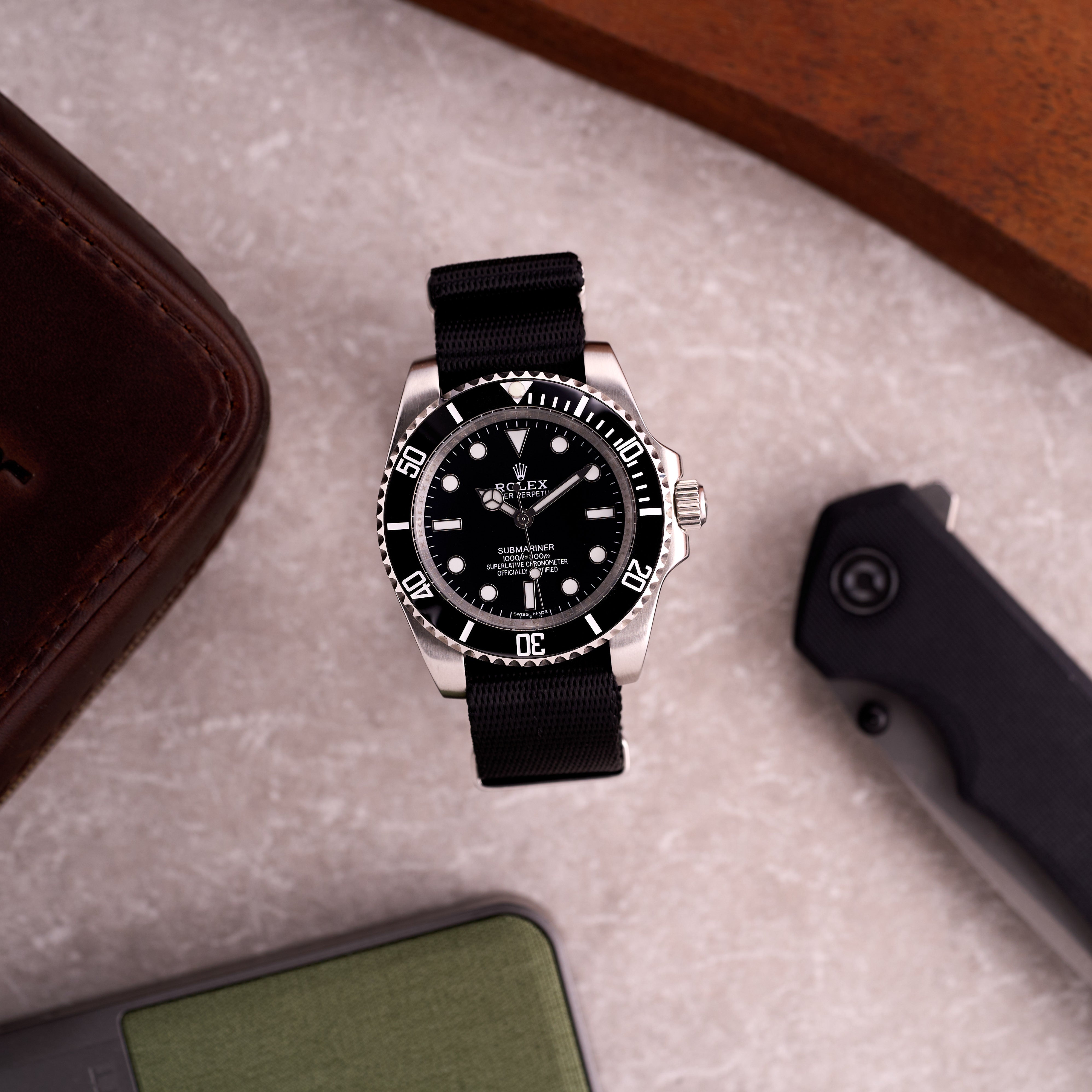 Tool watch on The Sentinel black seatbelt NATO strap worn on the wrist, showing sleek black nylon and low-profile keepers.