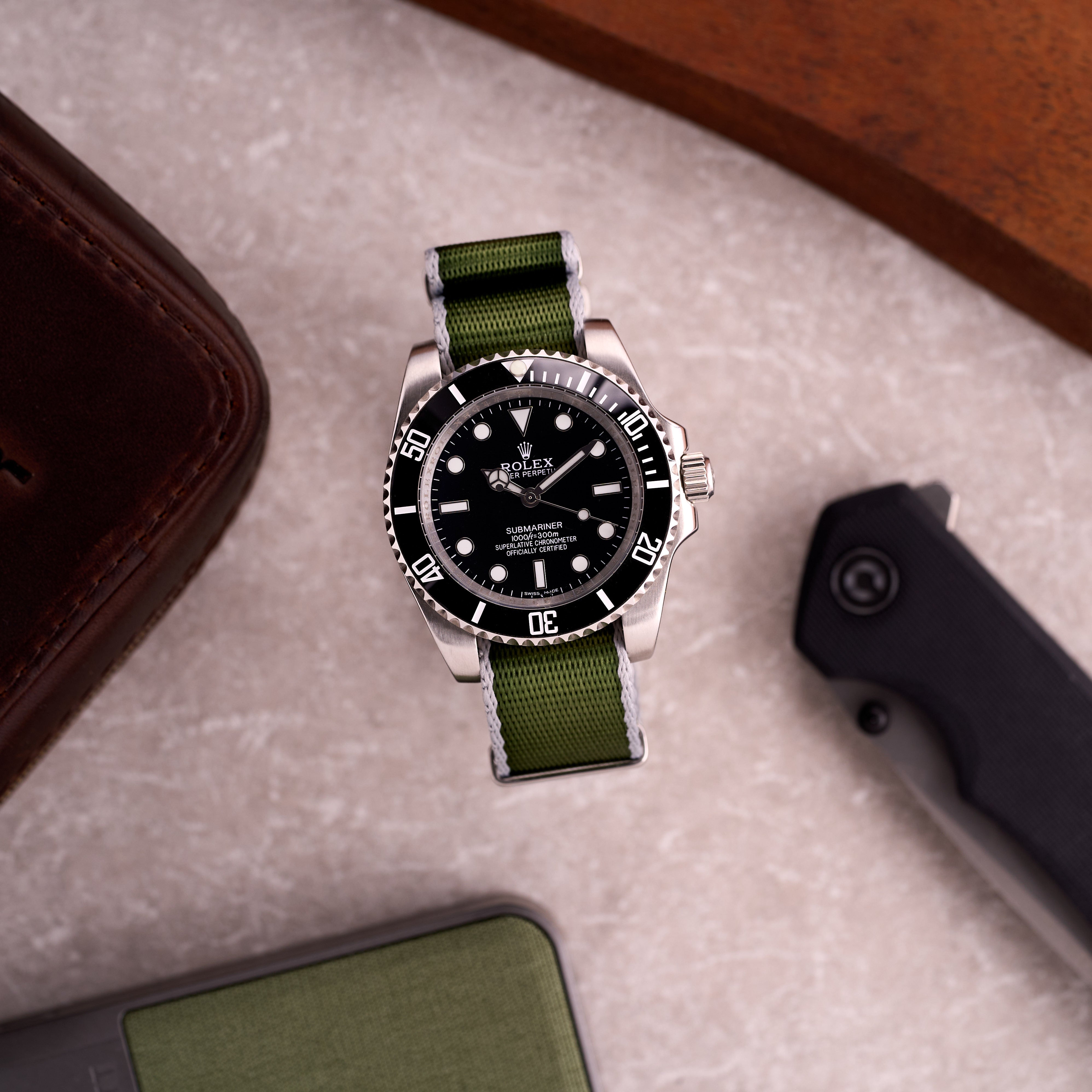 Watch on The Sentinel green with grey edge NATO strap in a lifestyle scene, showing the subtle grey-edged seatbelt design on wrist.
