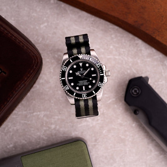 Dive watch on The Sentinel James Bond black and grey striped seatbelt NATO strap, creating an iconic Bond-style wrist shot.