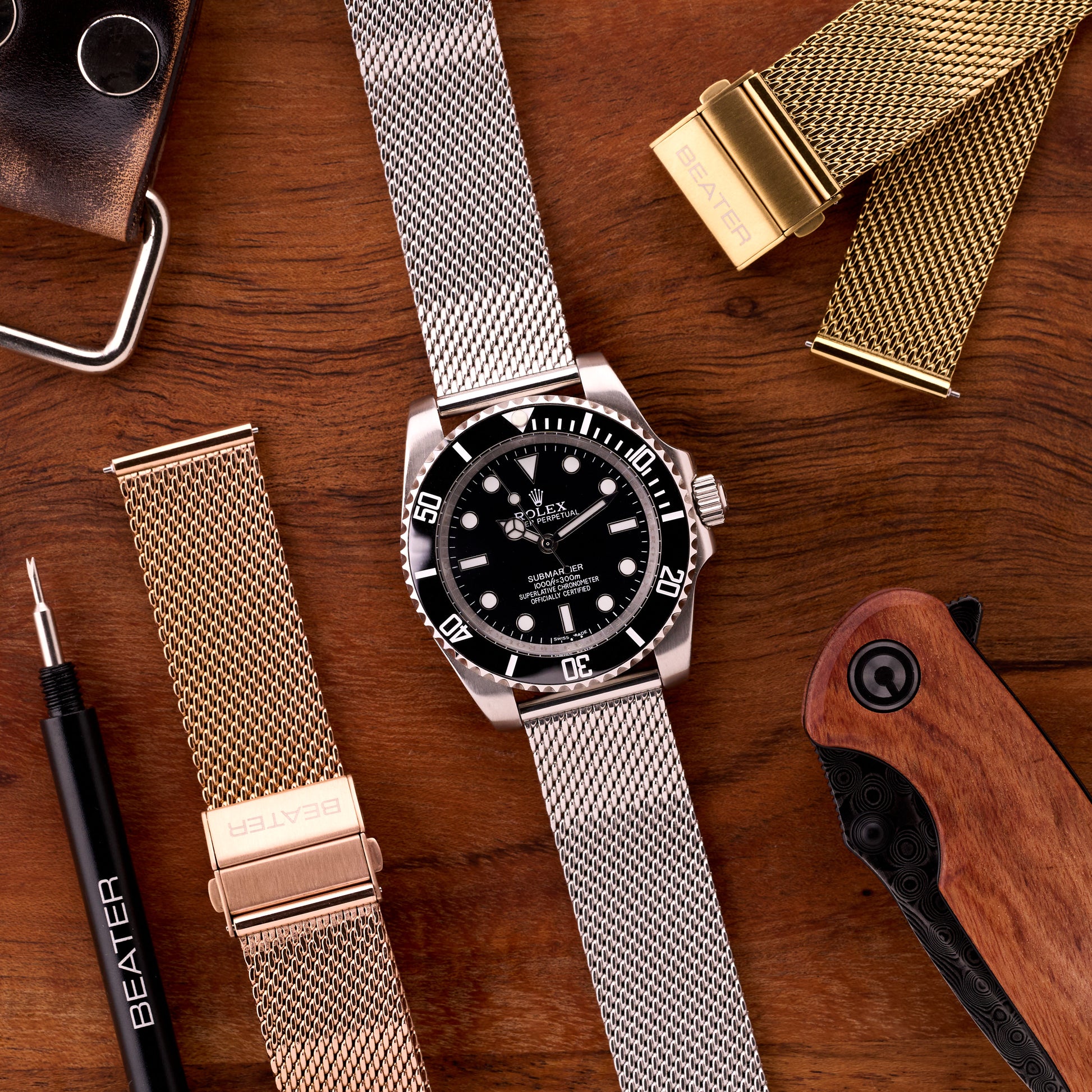 Flat lay of silver gold and bronze rose Sterling mesh bracelets with dive watch and tools, emphasising the warm bronze rose finish.​